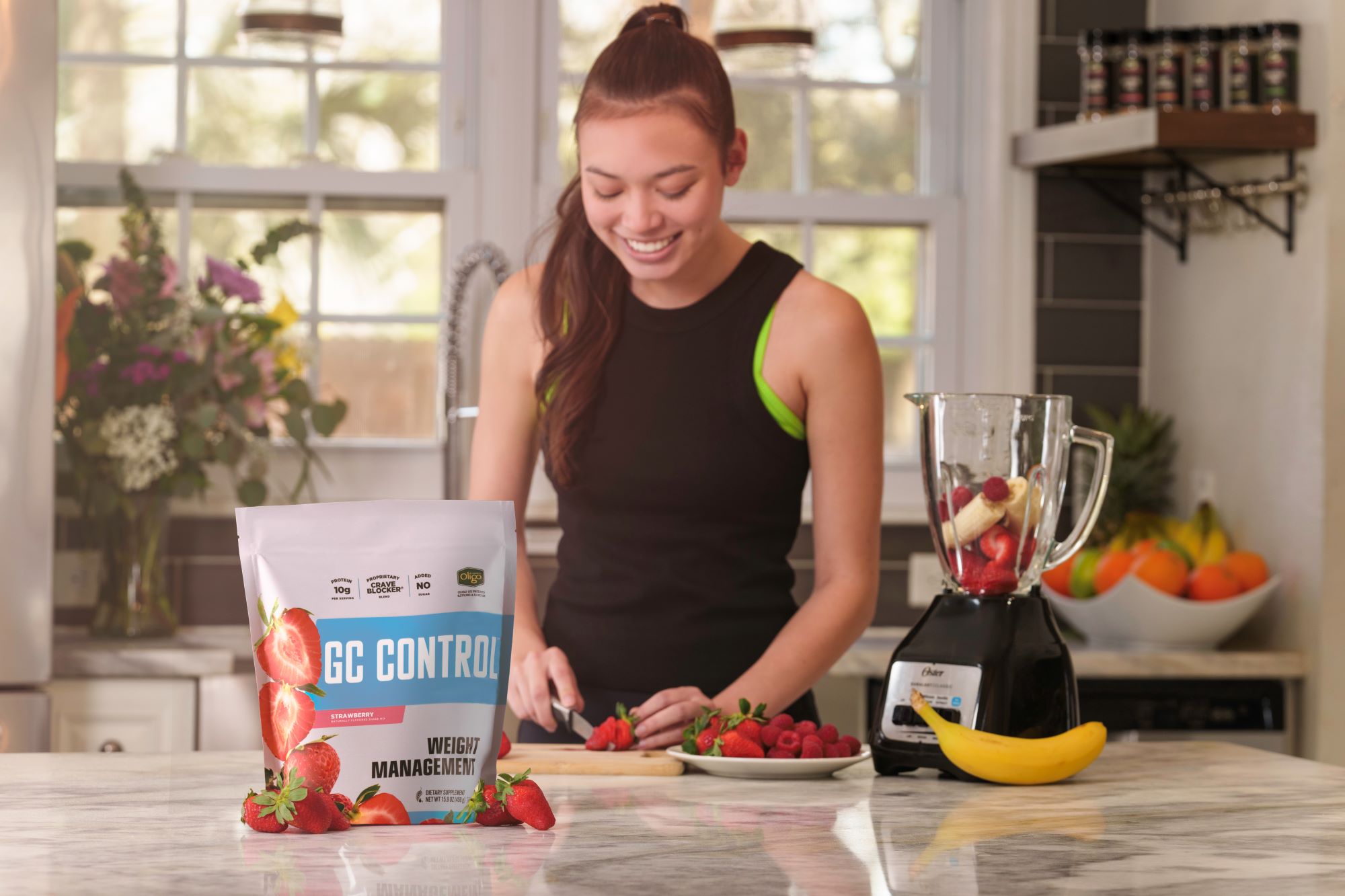 A young woman cutting fruit in a kitchen, with a package of GC Control on the counter.