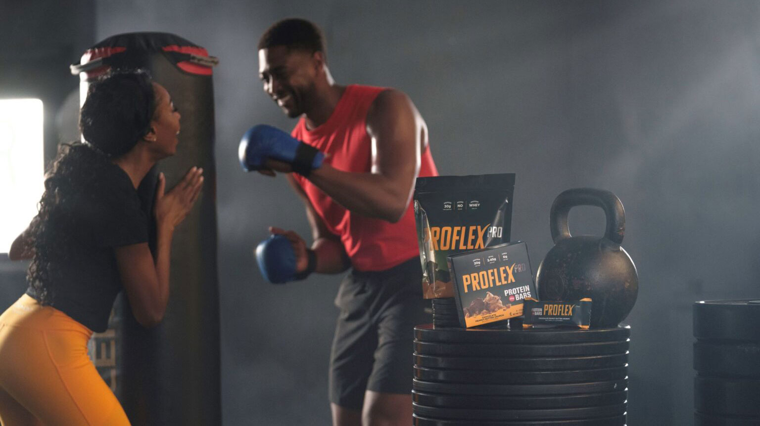 A black couple exercising at the gym together, with Melaleuca Proflex products in the foreground.
