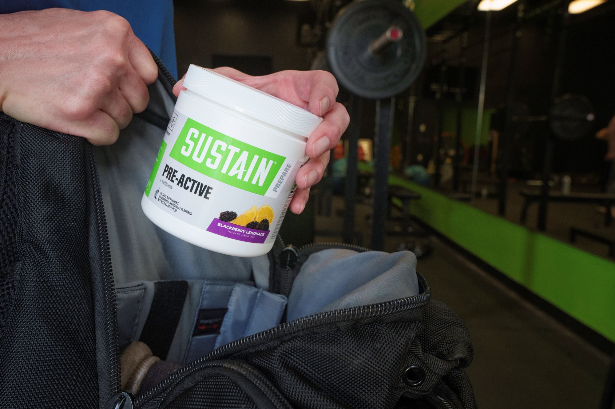 A man pulling Melaleuca Sustain Pre-Active out a bag while at a gym.